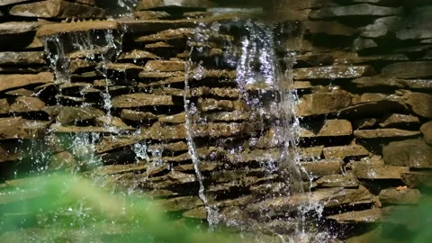 Stone wall with a waterfall in the garden. Artificial decorative waterfall Stock Footage 139738156