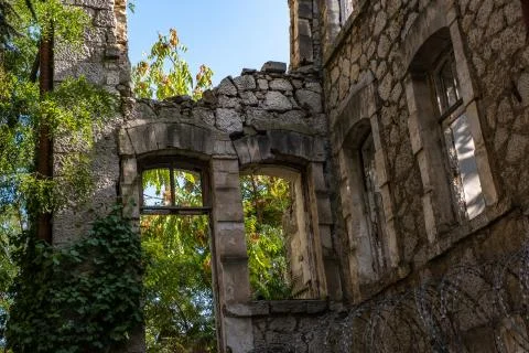 Stone walls of a destroyed building with window openings and barbed wire. Stock Photos