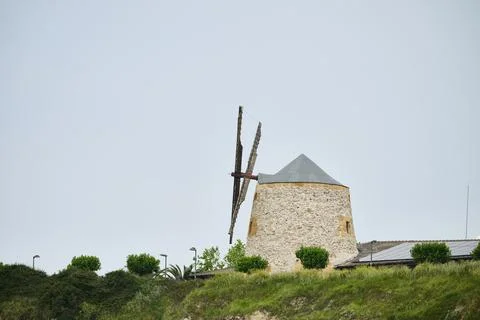 Stone windmill structure standing on green hill Foto stock