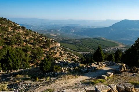 Stone window frames view of sunlit valley and distant hills. Warm tones highl Stock-Fotos