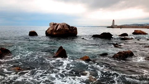 Stones at bay with lighthouse in the background Stock Footage 89813419