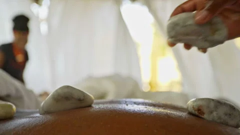 Stones being placed on a person's back during a stone massage at Mangwanani spa Stock Footage 289189961