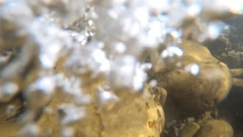 Stones at the bottom of a mountain river and air bubbles Stock Footage 141486299