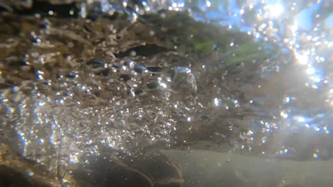 Stones at bottom of shallow river, air bubbles and fast strong stream water Stock Footage 141682958