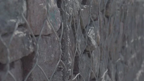 Stones in a chain-link mesh, wall of stones Video stock 278397544