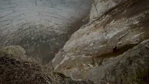 Stones fall down the cliff into ice-covered water. Stock Footage 138894692