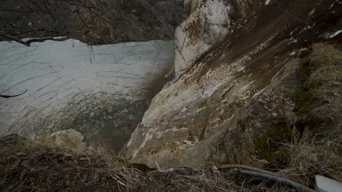 Stones fall down the cliff into ice-covered water. Stock Footage 138895720