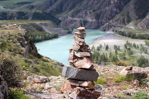 Stones lined with a tower against the backdrop of a blue river, mountains and Stock Photos