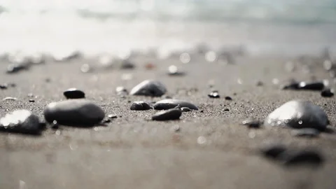 Stones pebble laying down on the sandy beach in the water waves and ocean foam Video stock 145617472