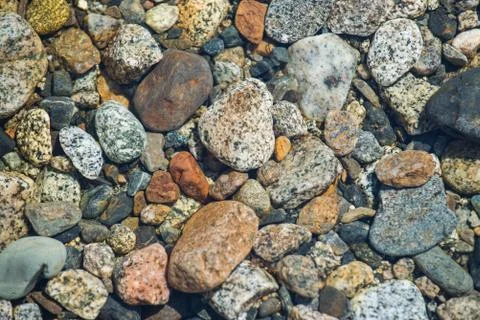 Stones in river of different shape and colors, closeup. Stock Photos
