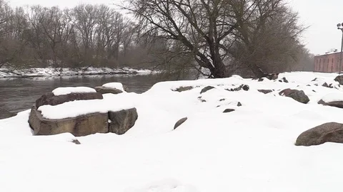 Stones under the snow in winter support the old bridge over the river Stock Footage 73683473