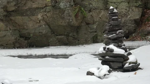 Stones on wintry river covered snows. Stack of pebble stones on snow. Stock Footage 86737221