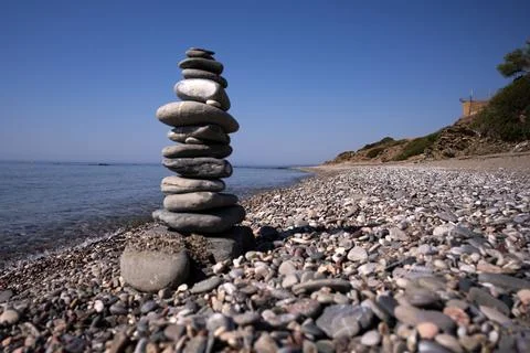 A stonework of flat pebbles keeps an even balance on the sea beach under th.. Stock Photos