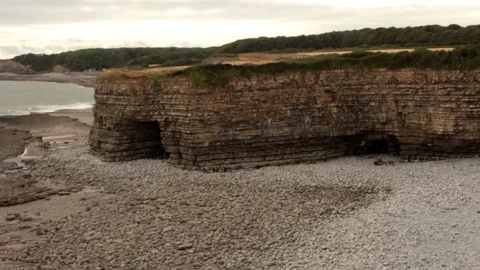 A Stony Beach Beneath a Clifftop with Fields and Trees in the Background Video stock 93167453