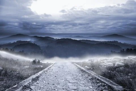 Stony path leading to large misty mountains Stock Illustration