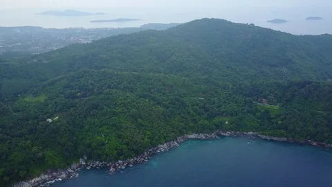 Stony shore and green forested hill, aerial panorama of rural Phuket area Stock Footage