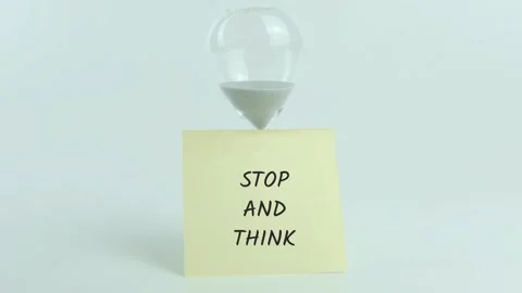 Stop and Think written on yellow sticky note placed on hourglass on white Stock Footage 313528995