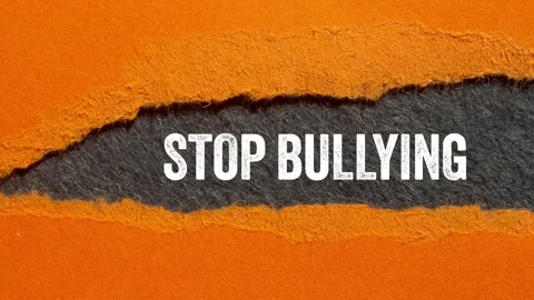 Stop bullying message writing on ripped torn orange paper on gray background Stock Footage 297260663