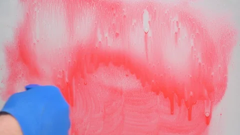 Stop coronavirus concept. hand in blue rubber glove washes glass from red paint Stock Footage 128807723