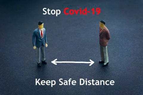 STOP COVID-19 KEEP SAFE DISTANCE text with miniature people on dark backgroun Stock Photos