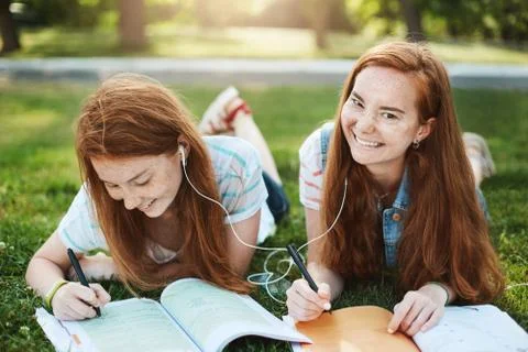 Stop fooling around and do homework. Two relaxed and carefree redhead sisters Stock Photos