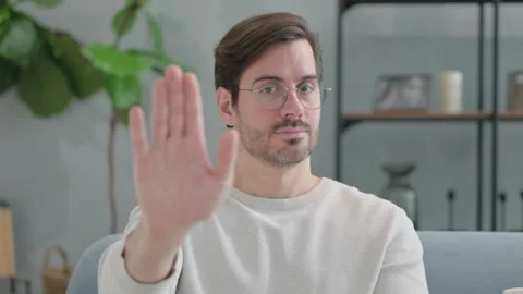 Stop Gesture by Young Man Sitting on Sofa at Home Video stock 286163838