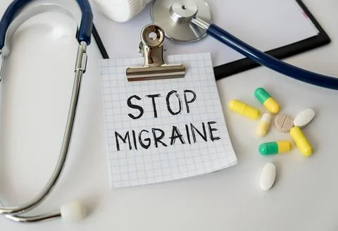 Stop Migraine text on a notebook on a table next to it is a stethoscope and.. Stock Photos