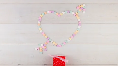 Stop Motion Animation Candy Heart with Arrow forming on White Wooden Background Stock Footage 100995217