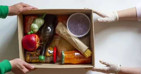 Stop motion animation. Donation box with various food, hands in medical gloves Stock Footage 129192696