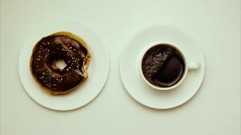 Stop motion, animation. Donut on a plate and a cup of coffee on a saucer. Top Stock Footage 73929054