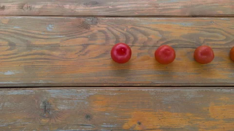 Stop motion animation line of tomatoes moving from right to left on wooden table Video stock 132460223