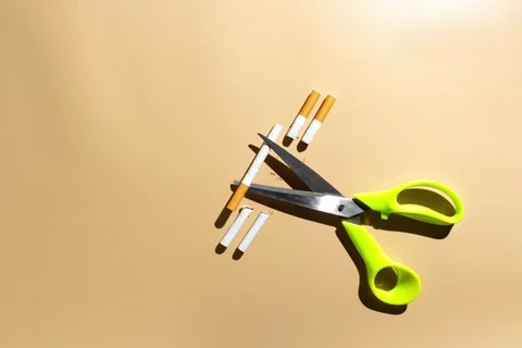 Stop motion animation of scissors cutting cigarettes on beige backround Stock Footage 287911714