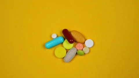 Stop motion animation of various pills filling the yellow background Stock Footage 240577862