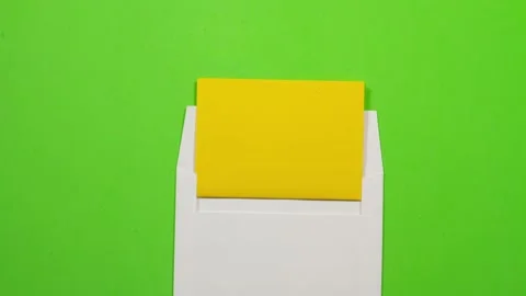 Stop motion animation of yellow paper getting into an envelope on green BG. Stock Footage 135424764