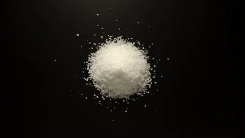 STOP MOTION: Coarse salt graines is piled up on the black table Vidéo 108199292