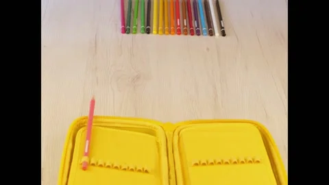 Stop motion of colored pencil going into a yellow pencil case Stock Footage 135254169