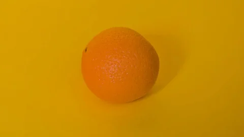 Stop motion colourful vibrant orange rotating on yellow background 4k Video stock 128227090