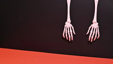 Stop Motion Halloween: Hanging Skeleton Arms on Orange and Black Background Stock-Footage 251651403