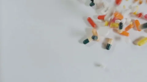Stop motion huge number of pills falling white background top view. Video stock 72880635