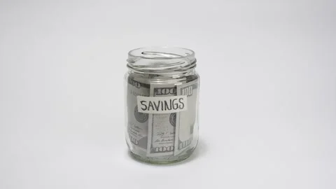Stop motion of jar with dollar bills dropping inside with the word Savings Stock Footage 317107570