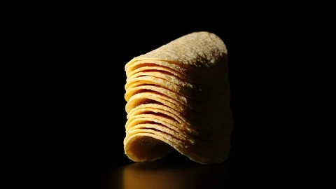 STOP MOTION: Potato chips are being stacked on a black surface - Front View Stock Footage 104482226