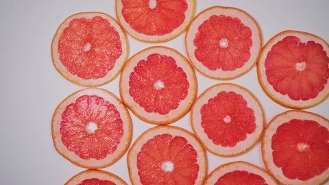 Stop motion, round slices of grapefruit and orange appear on white surface 스톡 동영상 125894270