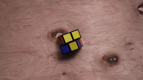 Stop motion of the rubik's cube moves on a light, wooden background.  Stock Footage 166238990