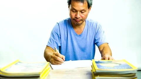 Stop motion of  Thai man  writing book with pile of books on the desk,  in studi Stock Footage 147115780