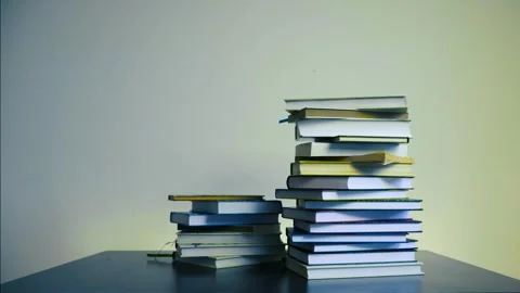 Stop motion video of books piling on top of each other, slowly increasing and Video stock 306357187
