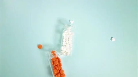 Stop motion video. Two glass jars on the table, from which pills pour out. Video stock 143666742