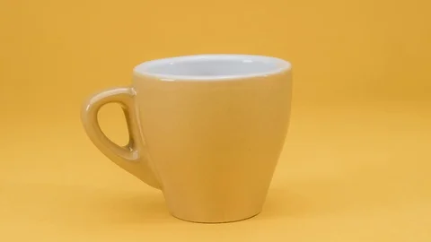 Stop motion of a yellow coffee cup rotating on a yellow background, 4k loop Stock Footage 128259214