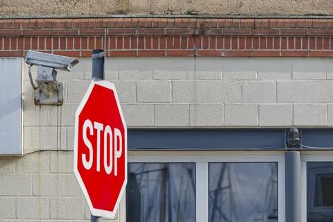 Stop Sign and Security Camera on Building Stock Photos