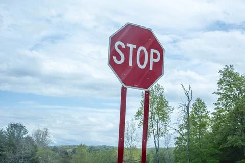 Stop sign under a cloudy blue sky. Stock Photos