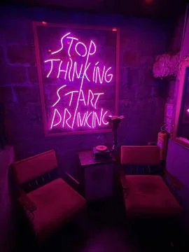 Stop Thinking Start Drinking LED NEON party sign in a night club Stock Photos